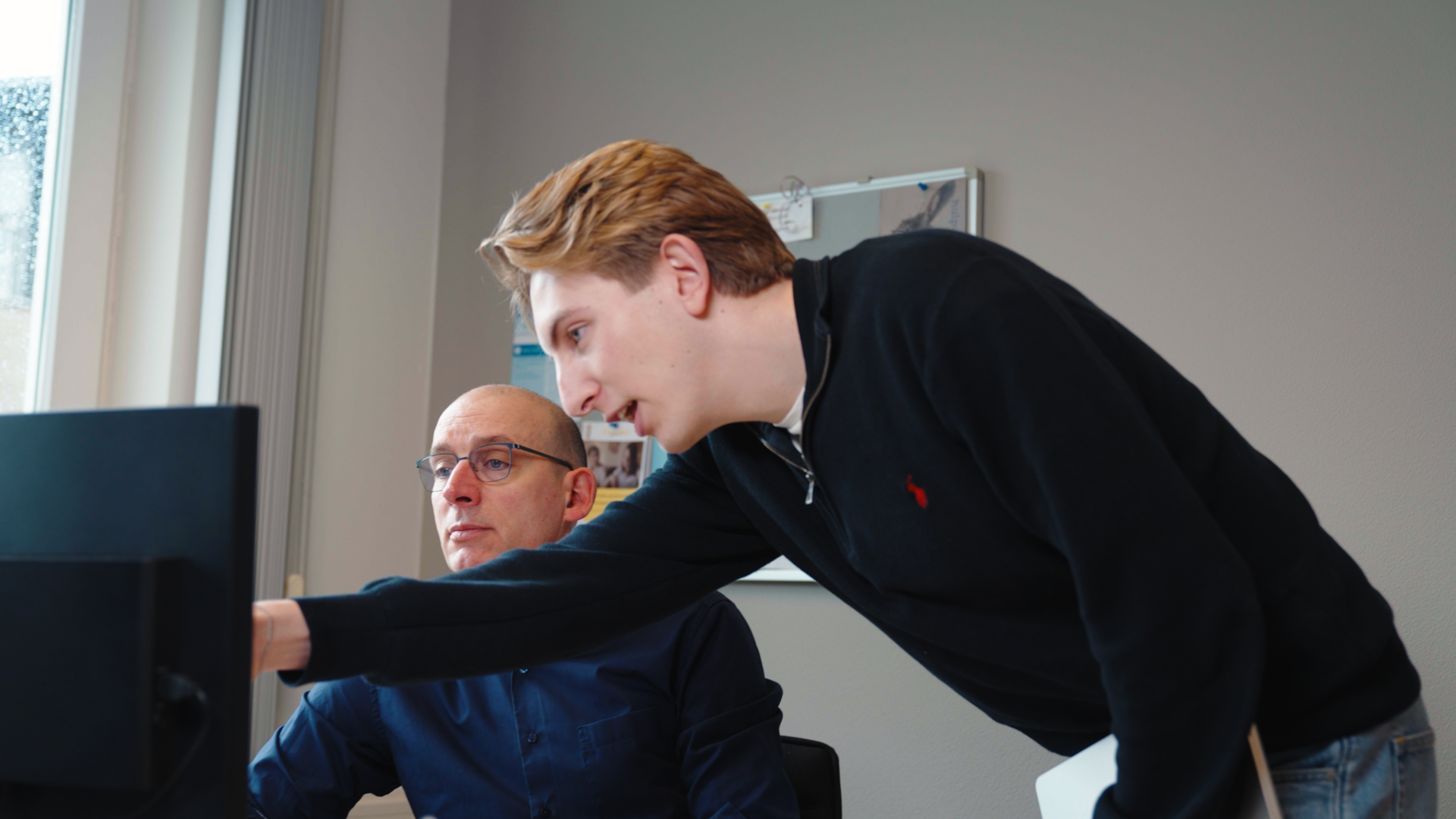 Twee collega's werken samen achter een scherm.